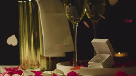Table-Set-For-Romantic-Marriage-Proposal-With-Confetti-Champagne-And-Engagement-Ring
